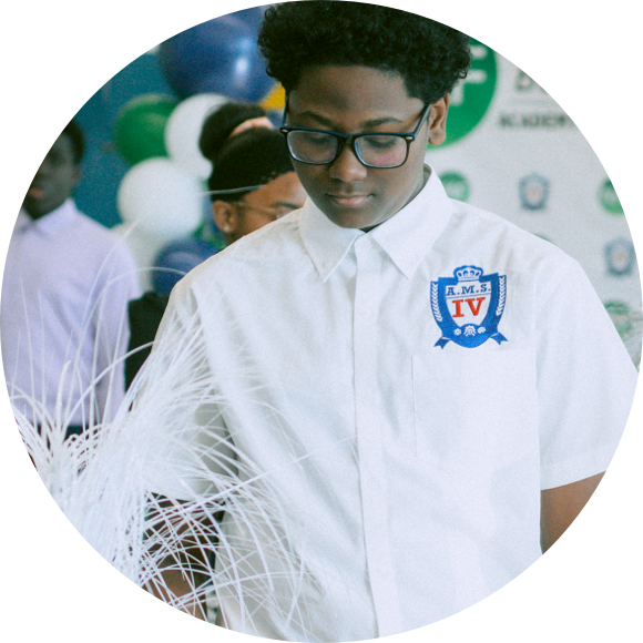 A person wearing glasses and a white shirt with an "RMS IV" logo stands in front of a backdrop with various logos and balloons.