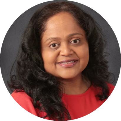 A person with long, curly black hair, wearing a red shirt, smiles against a gray background.